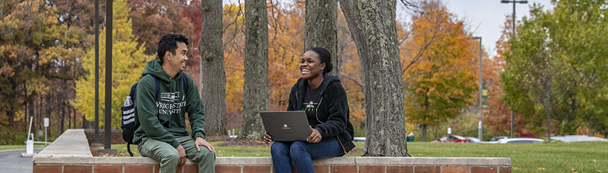photo of two students sitting outside on campus