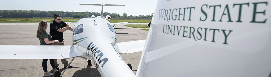 photo of a student and instructor standing by an airplane