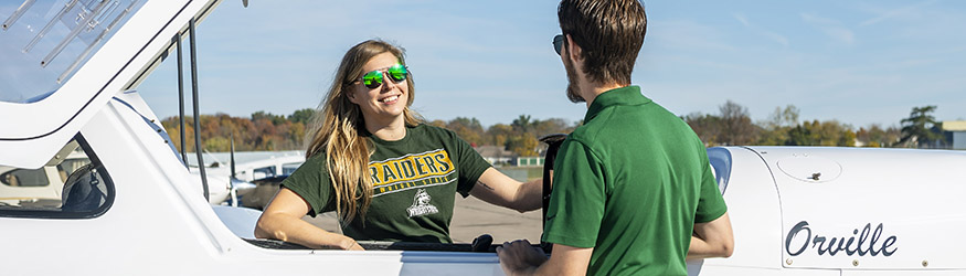 photo of a student an instructor beside a plane