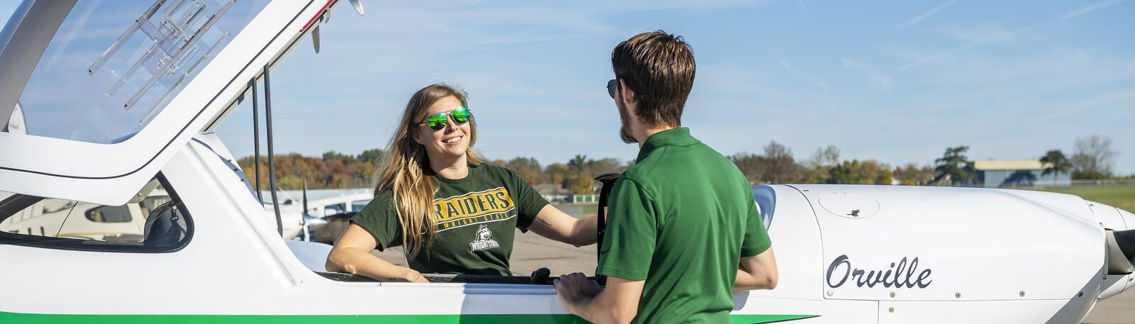 photo of a student and an instructor next to a plane
