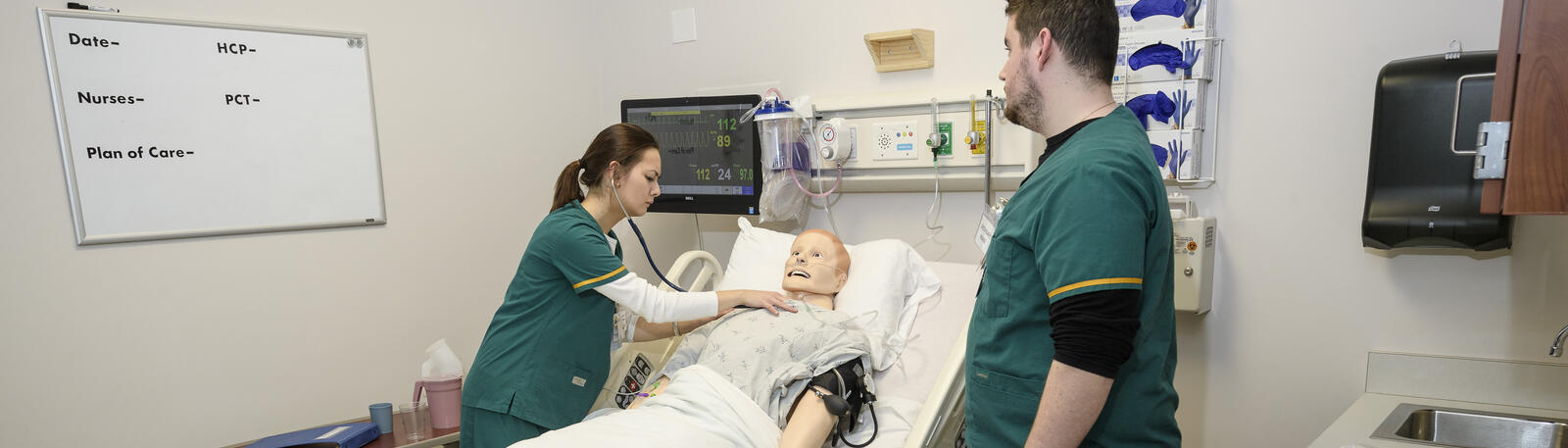 photo of two nursing students with a simulated patient