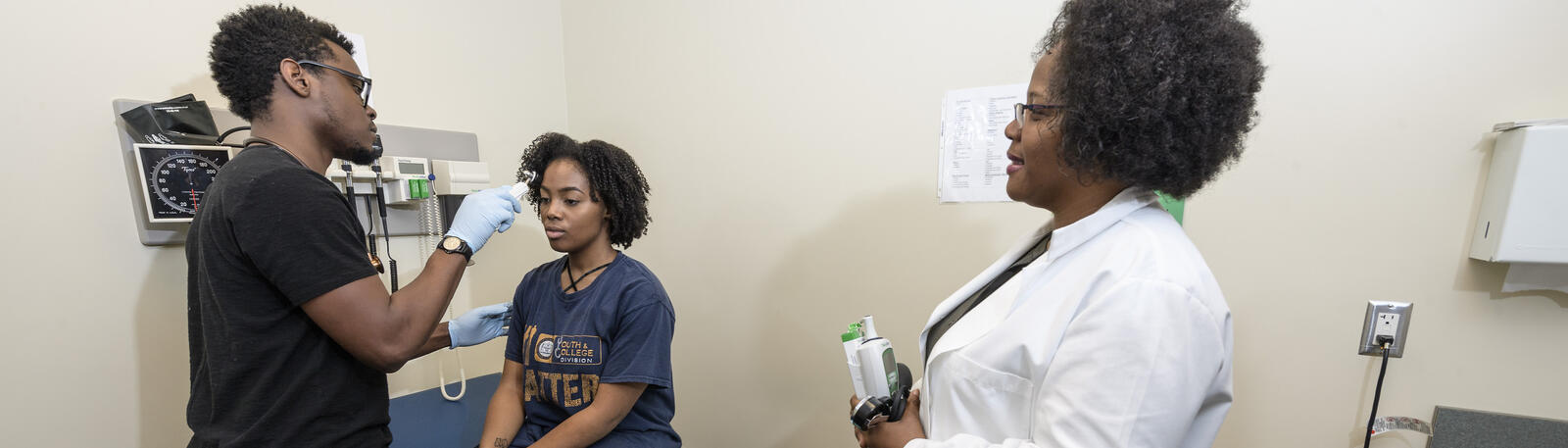 photo of a nursing student, an instructor, and a patient in an exam room